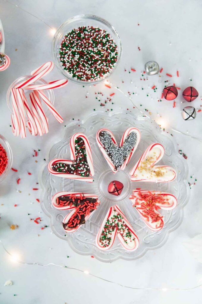 A festive spread featuring easy candy cane hearts on a white counter with sprinkles and candy canes