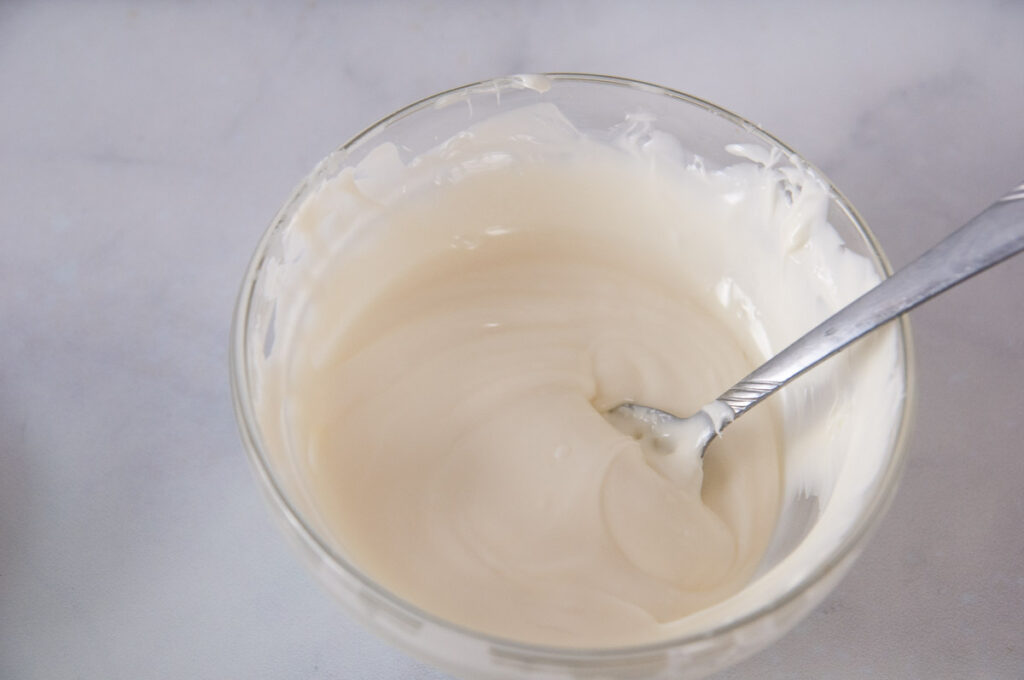 A bowl of melted white chocolate on a white counter