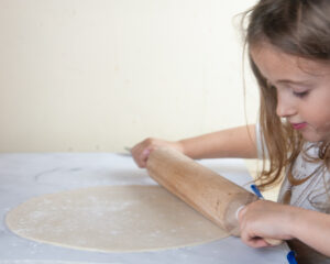 A child rolling out pie crust