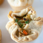Mini chicken pot pies on white platters in a white kitchen. These pot pies are a kid and freezer friendly way to use up leftover chicken or turkey.