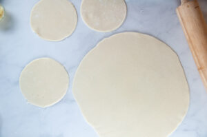 Pie crust rolled out to a 13 inch circle with 3 5 inch rounds on white