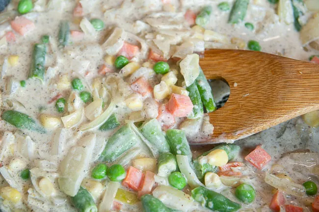 A skillet full of vegetables in a white sauce