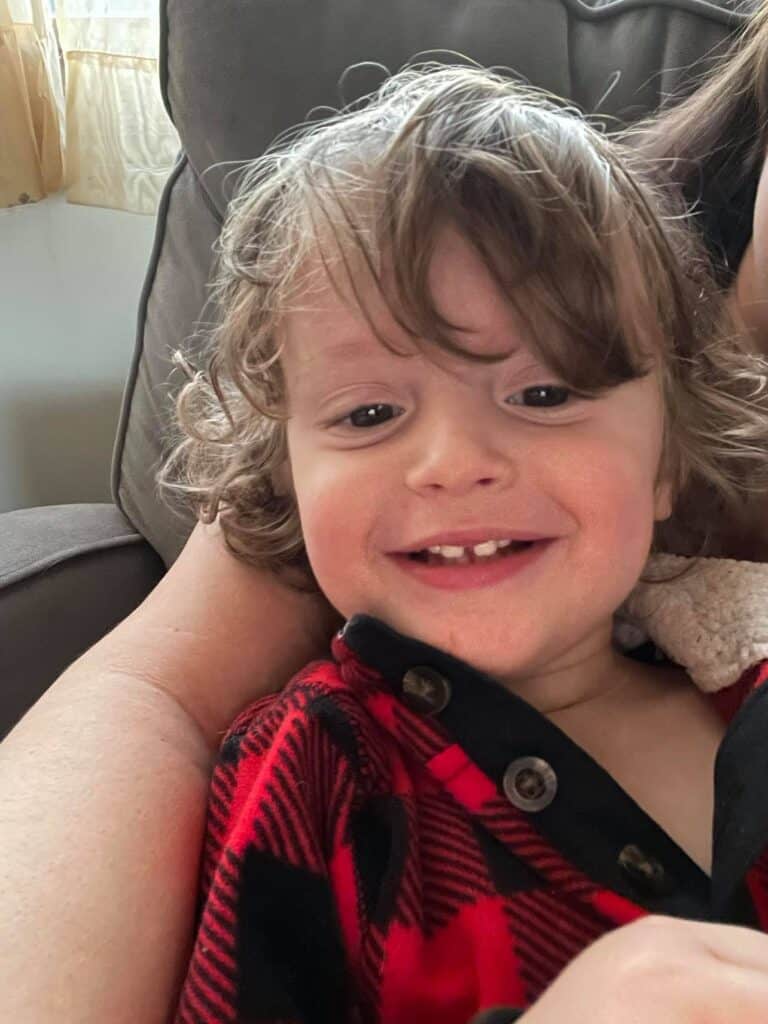 toddler boy smiling with hair in his eyes