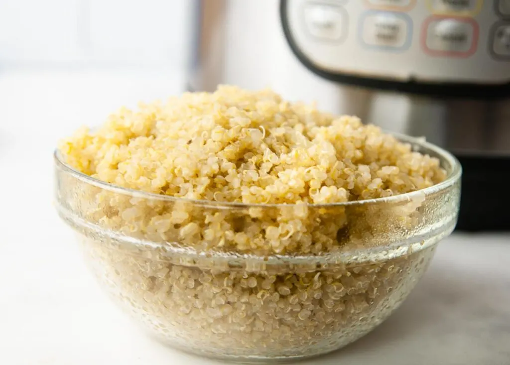 Making quinoa in the Instant Pot is perfect for meal prep. A bowl of quinoa in front of the pressure cooker.
