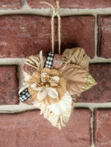 Embellished twine heart hanging against a brick wall.