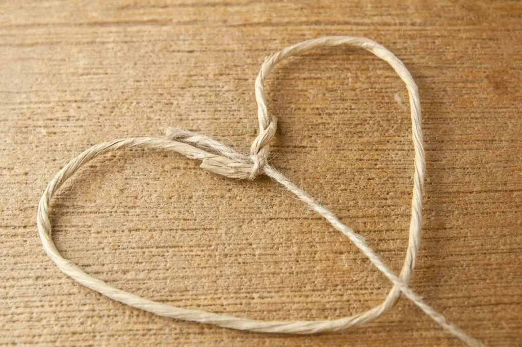 A floral wire heart shaped frame with twine tied to the v of the heart