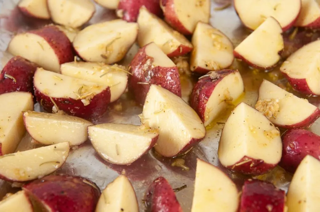 Toss the cut red skin potatoes in olive oil and season them with salt, pepper and garlic before you spread them on a prepared tray.