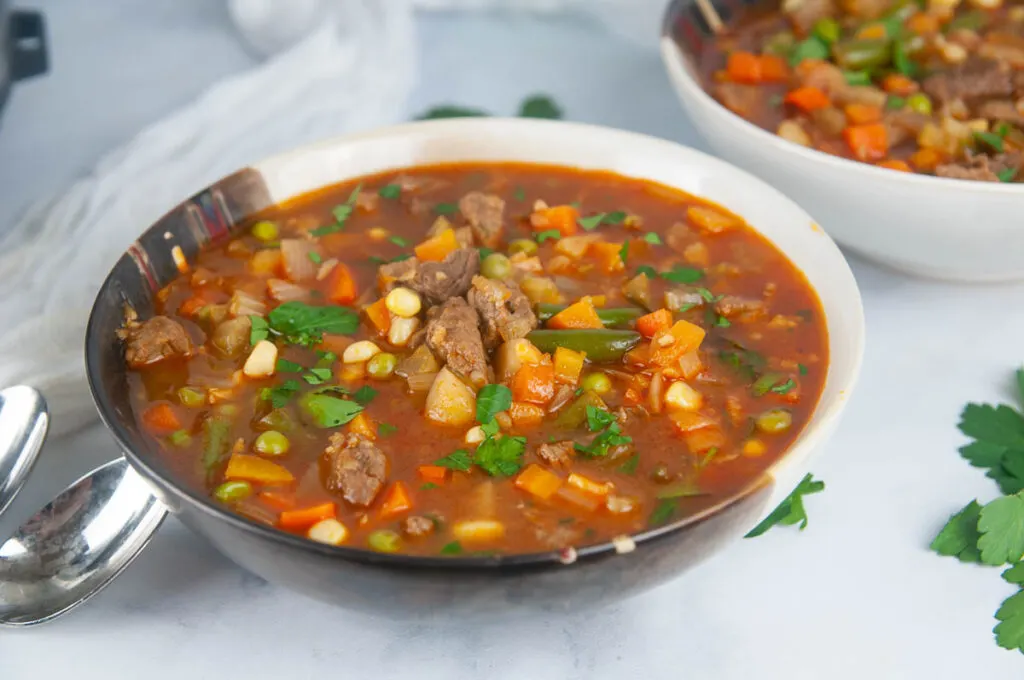 A bowl of hearty Instant Pot vegetable beef soup ready for a cozy dinner on a white background.
