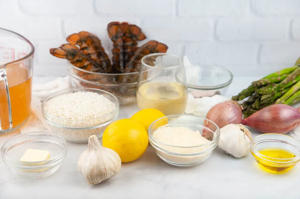 Ingredients needed for lobster risotto: white wine, vegetable broth, butter, olive oil, lobster tails, risotto, Parmesan cheese, garlic cloves, lemon juice, salt, pepper, and shallots.