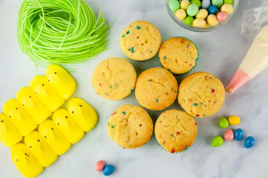 Ingredients for Easter cupcakes: cupcakes, buttercream, chick peeps, edible Easter grass, candy coated eggs