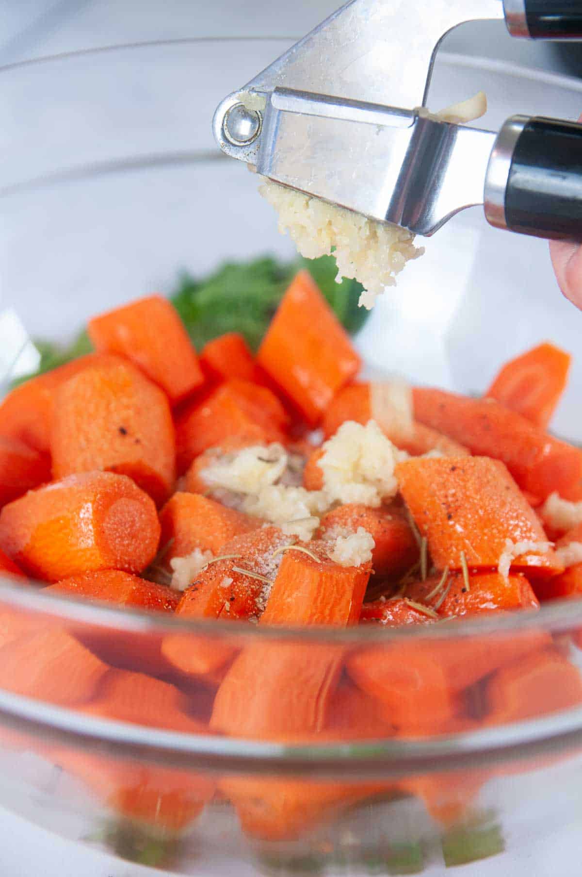 Season the carrots with fresh pressed garlic and herbs.