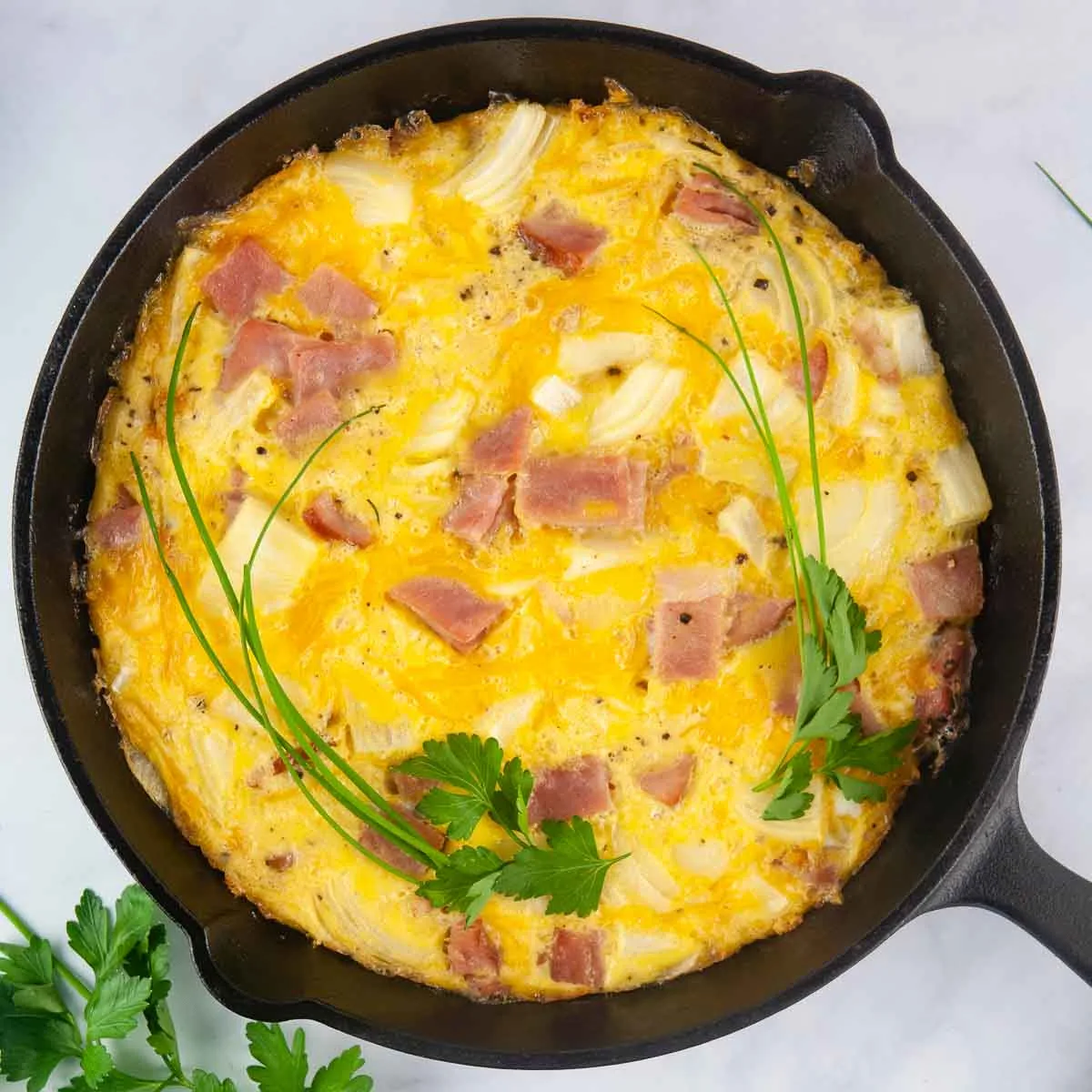 Ham and Cheese Frittata is a kind of crustless quiche shown in a cast iron skillet that makes a lovely breakfast or brunch>