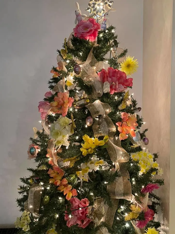 a christmas tree decorated for spring with pink and yellow flowers, butterflies, and burlap