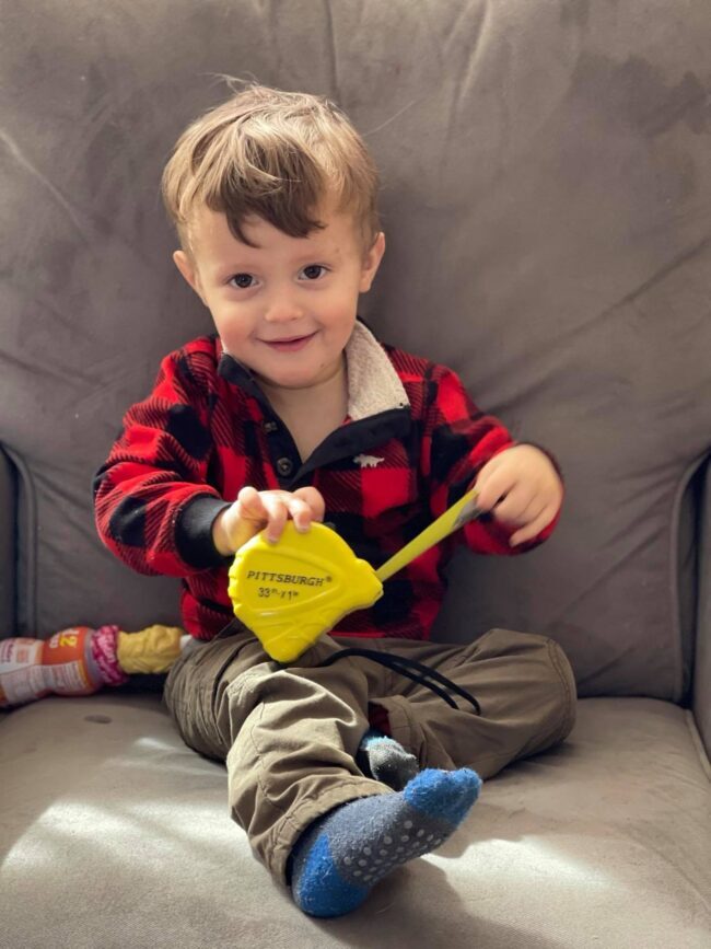 toddler holding a measuring tape