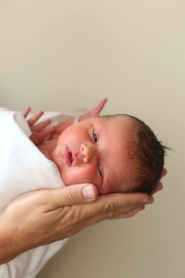 newborn baby in adult's hands