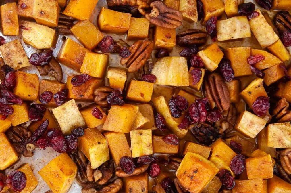 A tray of cinnamon sugar butternut squash out of the oven and tossed with cinnamon, brown sugar and craisins