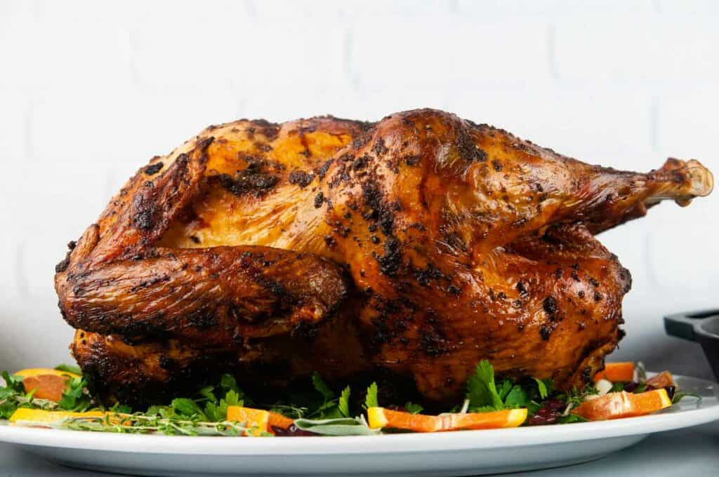 A butter basted turkey with golden, crispy skin on a serving platter