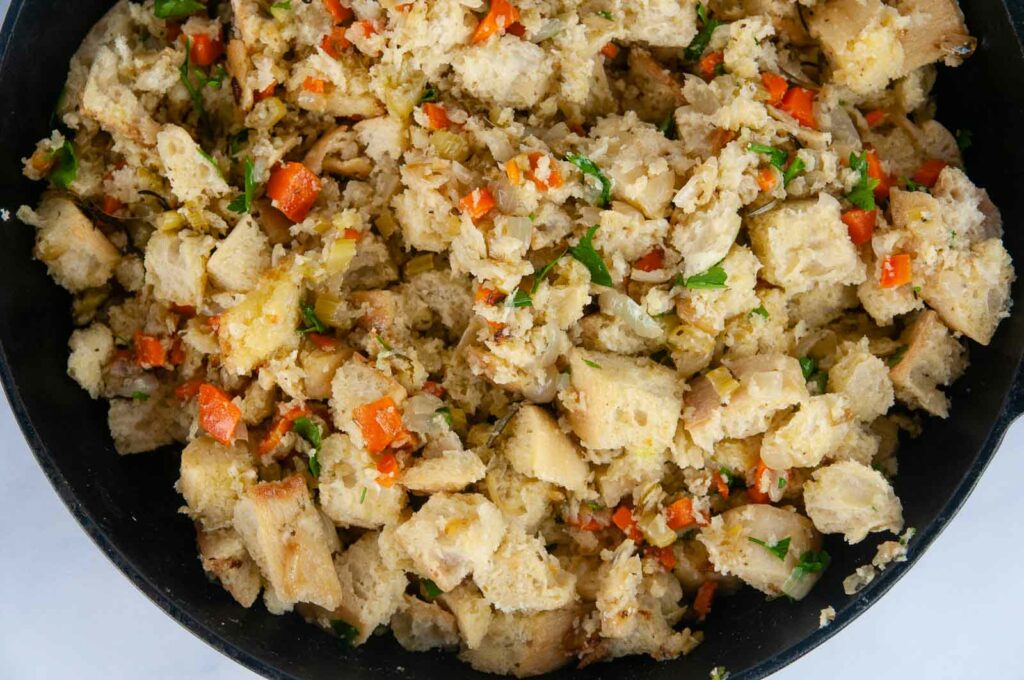 Toss the bread cubes with the cooked vegetables to make the vegetarian stuffing.