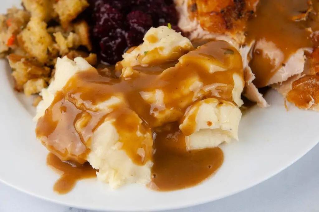 Roasted Garlic Mashed Potatoes covered in gravy pair well with any turkey, chicken, or roast beef dinner.
