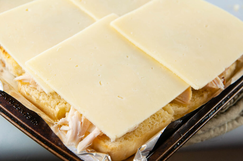 Layer the turkey and slices of cheddar cheese on to the prepared Hawaiian rolls.