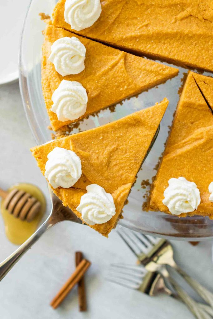 A perfect slice of no bake pumpkin cheesecake on a pie cutter above the rest of the cake