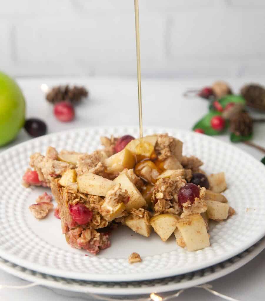 Cranberry apple baked oatmeal with a drizzle of maple syrup is a wholesome, festive breakfast.