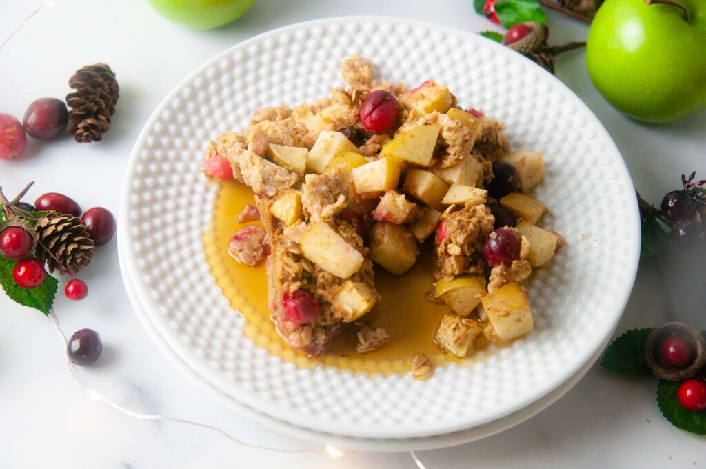 Cranberry apple baked oatmeal with a drizzle of maple syrup is a wholesome, festive breakfast.