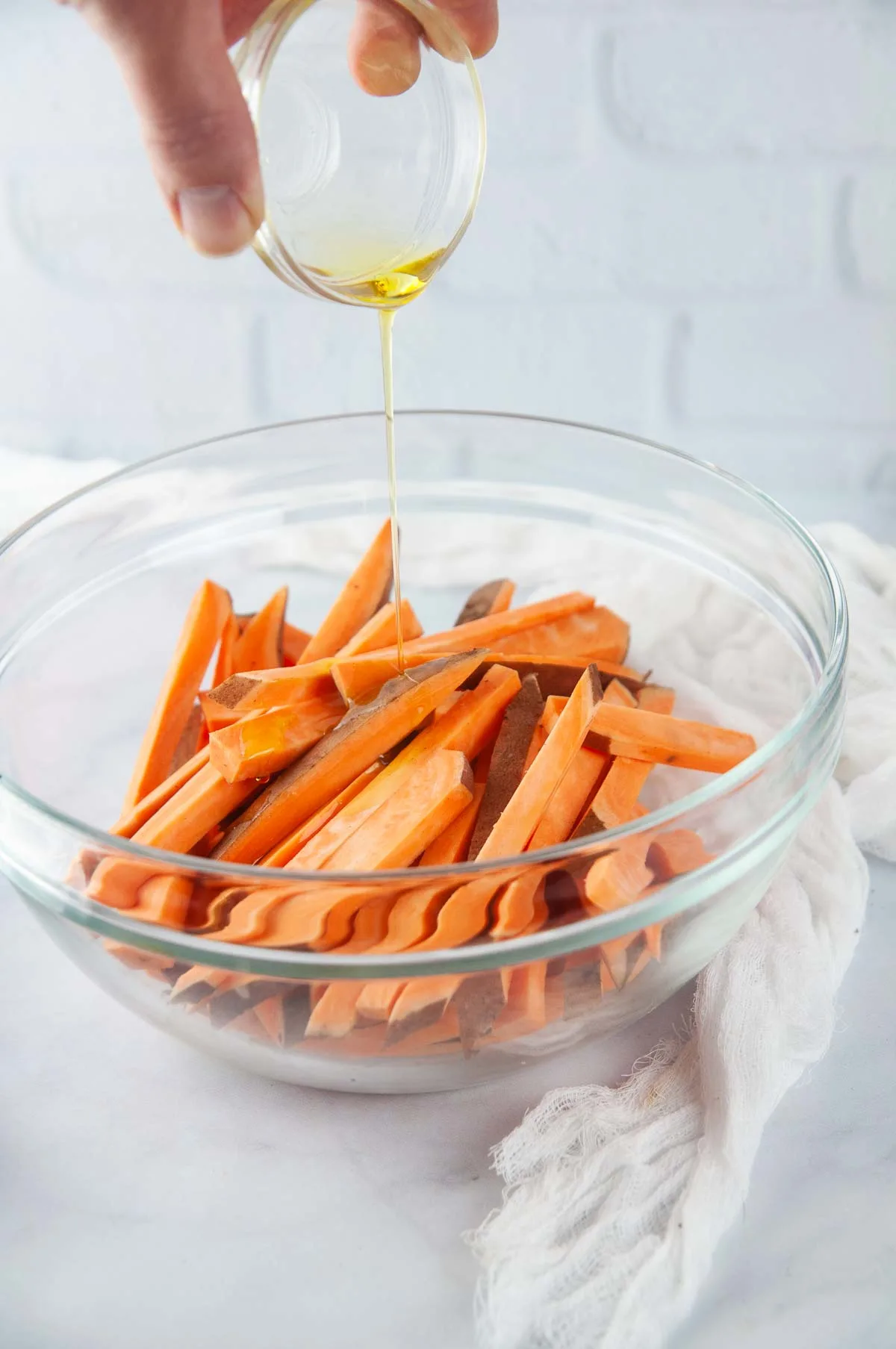 Put the cut sweet potatoes into a bowl to toss them with olive oil and your choice of seasoning.