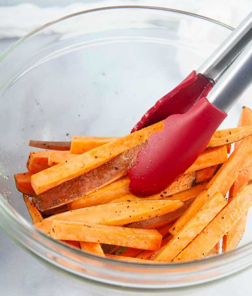 Toss the cut sweet potato fries with seasoning.