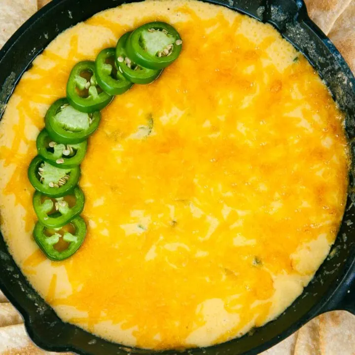 A tortilla chip gets dunked into creamy, cheesy jalapeno popper dip.