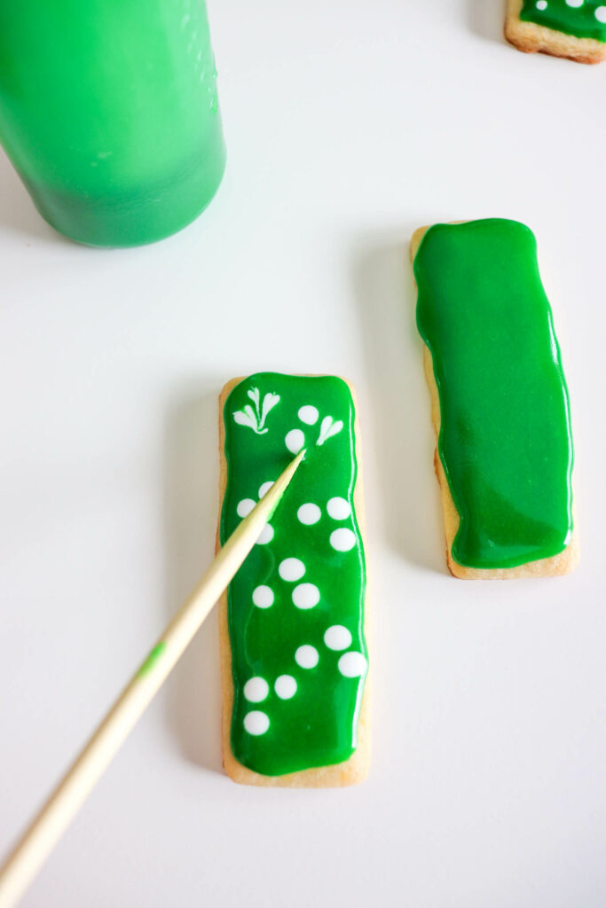 Make white polka dots on wet green royal icing and drag a toothpick from the top middle of the circles down to make a shamrock