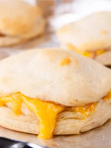 Bake the ham and cheese biscuit sandwiches until the tops are golden brown and the cheese melts.