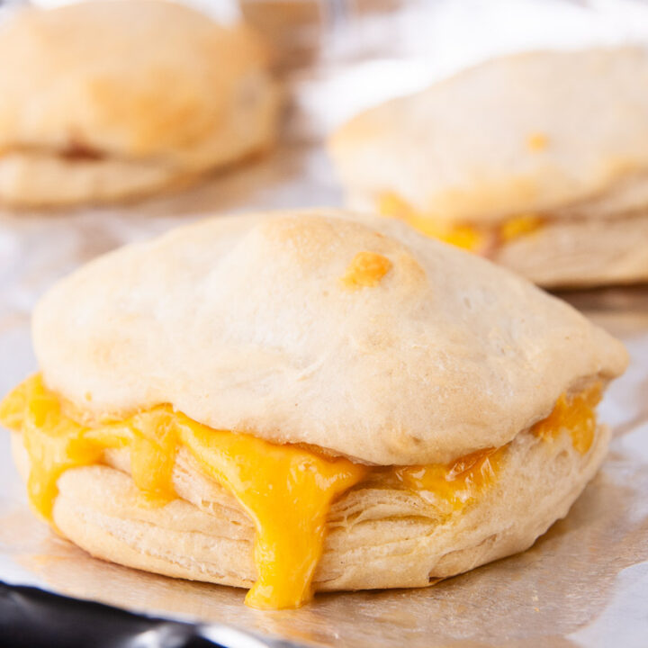 Bake the ham and cheese biscuit sandwiches until the tops are golden brown and the cheese melts.