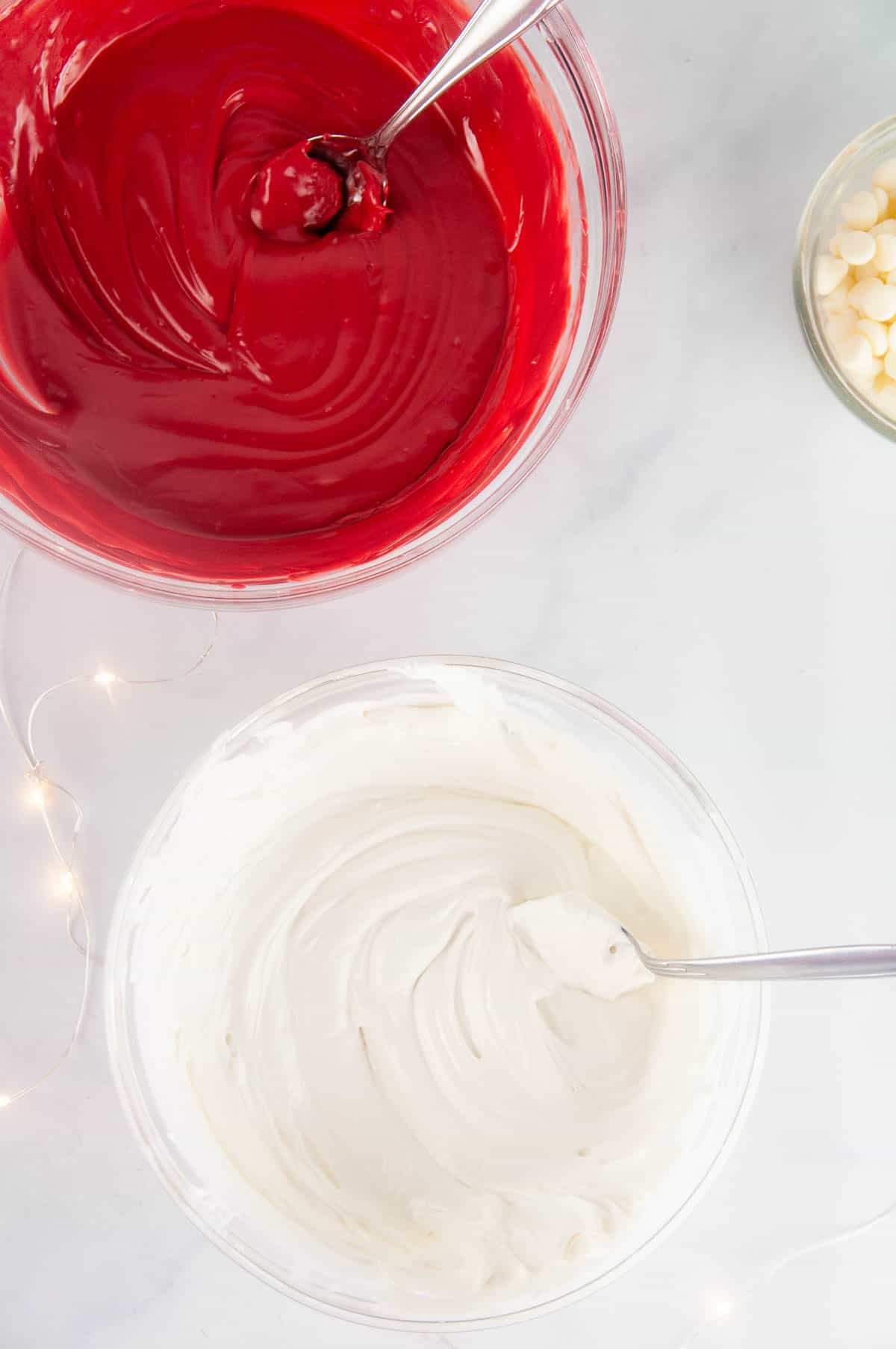 A bowl of white melted candy and a bowl of red melted candy