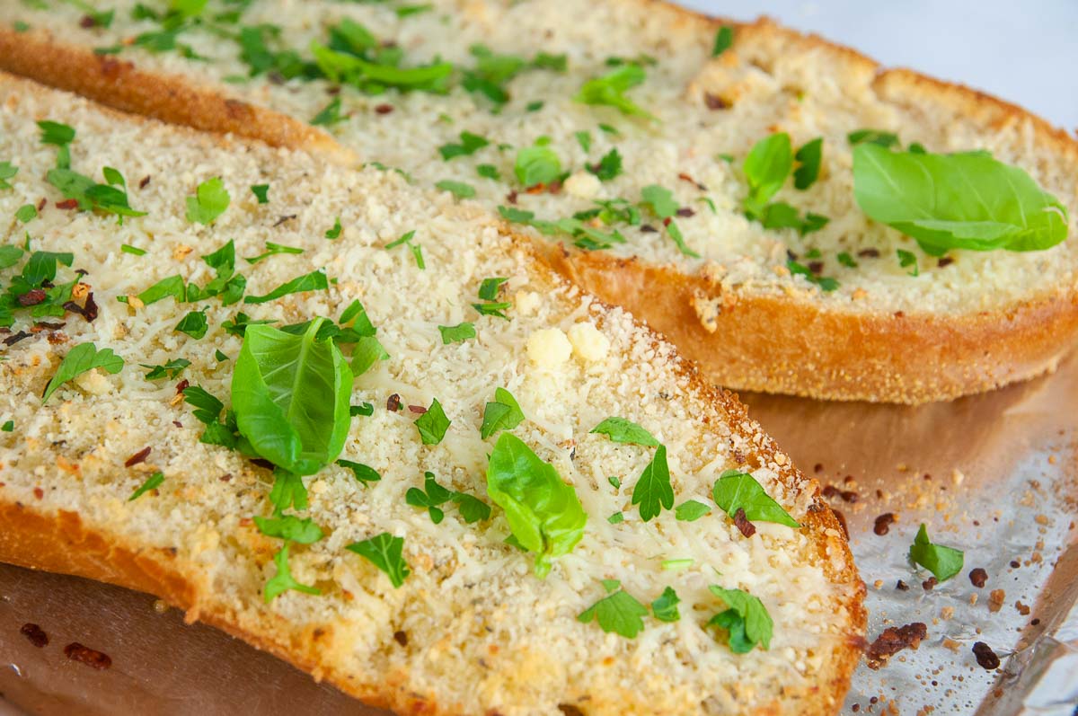 Finish the garlic bread with fresh basil leaves, and parsley.