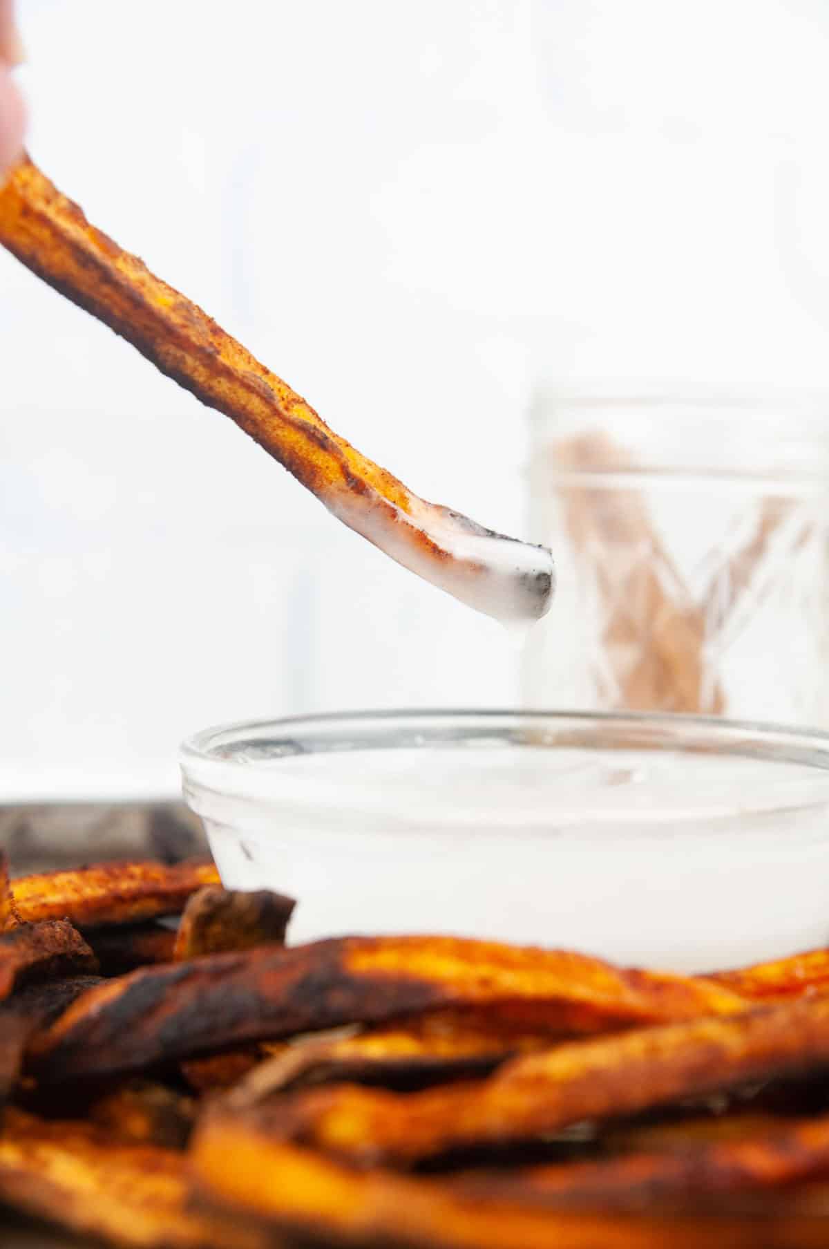 Dipping a cinnamon sugar sweet potato fry into powdered sugar glaze