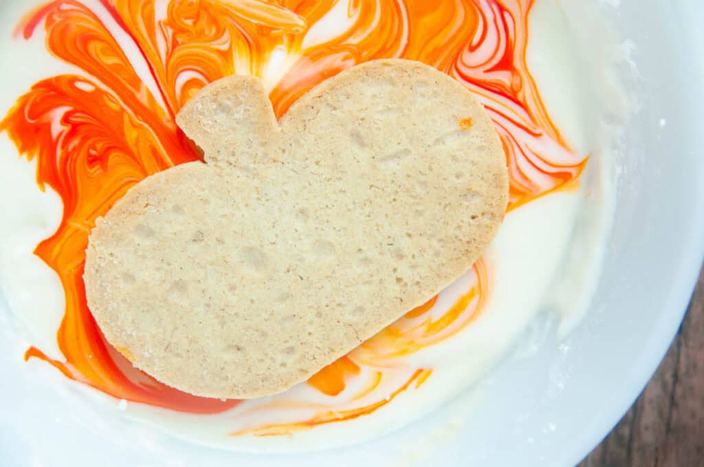 Dip the baked pumpkin cut out sugar cookie into the swirled icing.