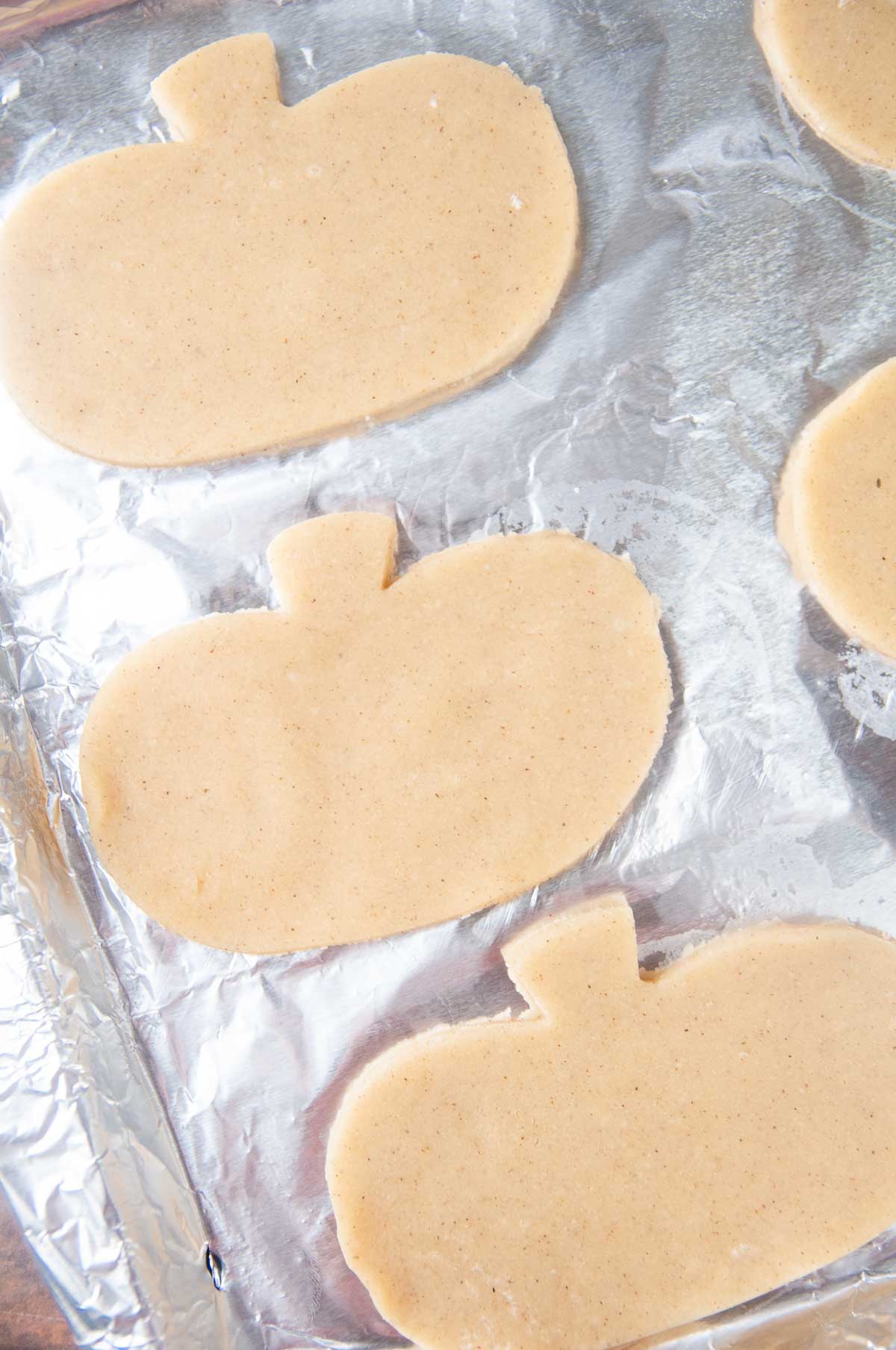 Cut out pumpkin spice sugar cookies on a foiled cookie tray- don't space them too close together
