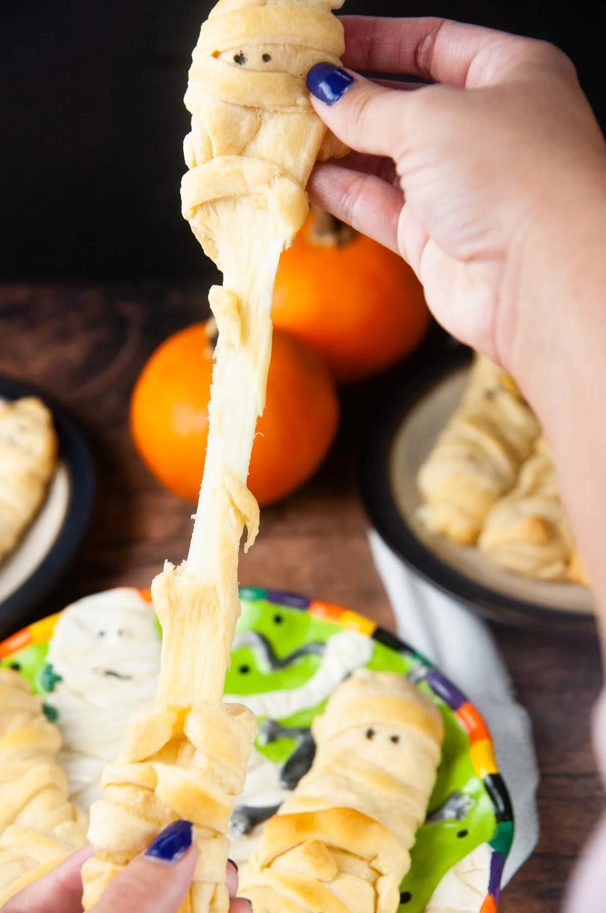 Mummy mozzarella sticks in crescent dough are an easy Halloween snack or appetizer both kids and adults love.