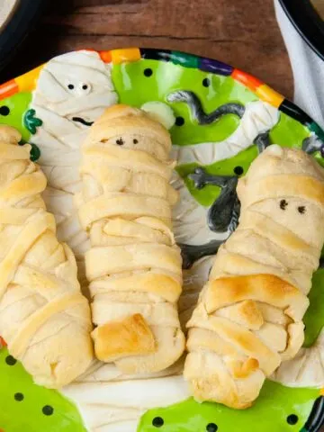 Mummy mozzarella sticks in crescent dough are an easy Halloween snack or appetizer both kids and adults love.