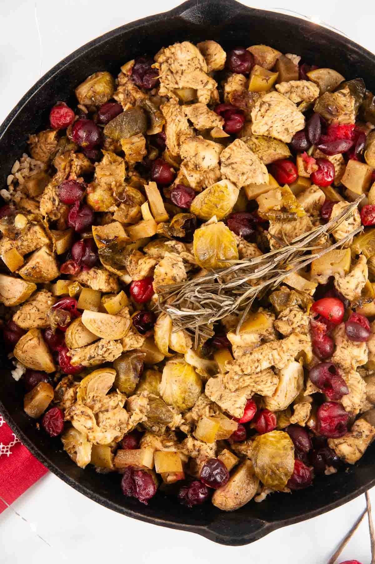 Cranberry Chicken is a festive, one skillet meal featuring tender chicken, juicy apples, Brussels sprouts, tart cranberries, and rice in a tangy sweet marinade.