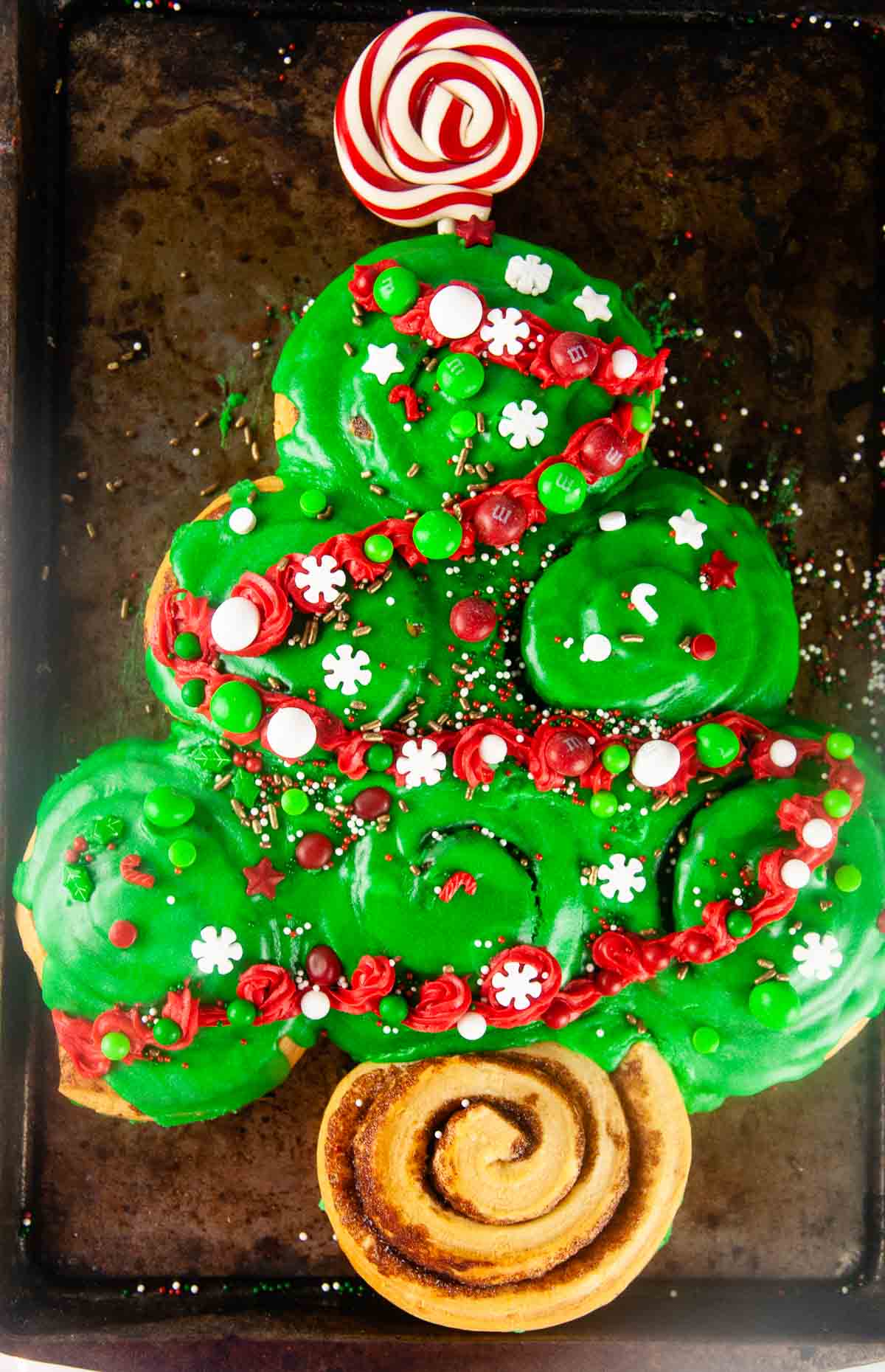Decorated with candy, sprinkles and red frosting garland, Easy Cinnamon Roll Christmas Tree for Christmas Morning makes a fun, kid friendly Christmas breakfast.