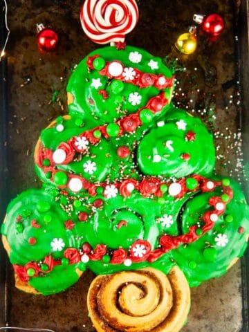 Decorated with candy, sprinkles and red frosting garland, Easy Cinnamon Roll Christmas Tree for Christmas Morning makes a fun, kid friendly Christmas breakfast.