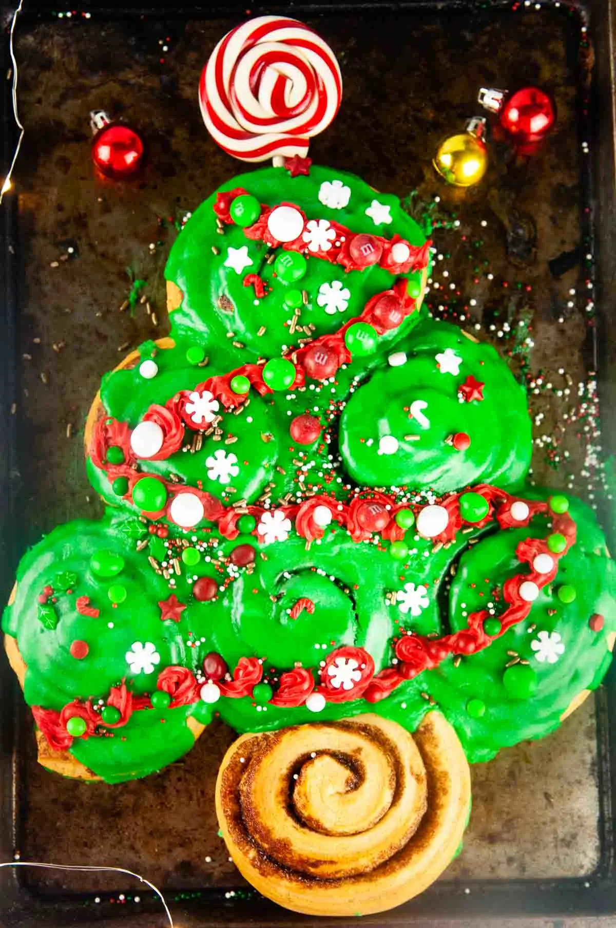 Decorated with candy, sprinkles and red frosting garland, Easy Cinnamon Roll Christmas Tree for Christmas Morning makes a fun, kid friendly Christmas breakfast.