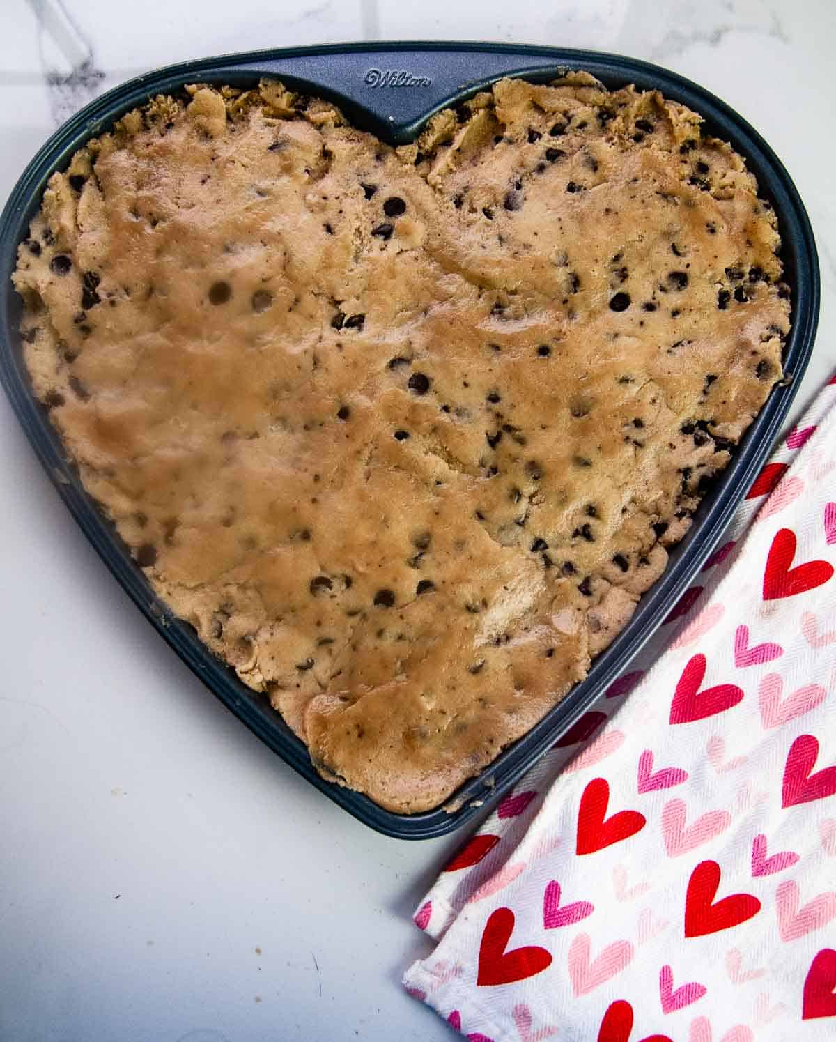 Chocolate chip cookie dough in a heart pan ready to be baked into a Valentine's Day treat.