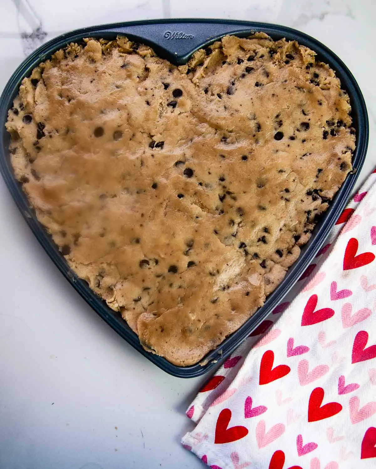 Chocolate chip cookie dough in a heart pan ready to be baked into a Valentine's Day treat.