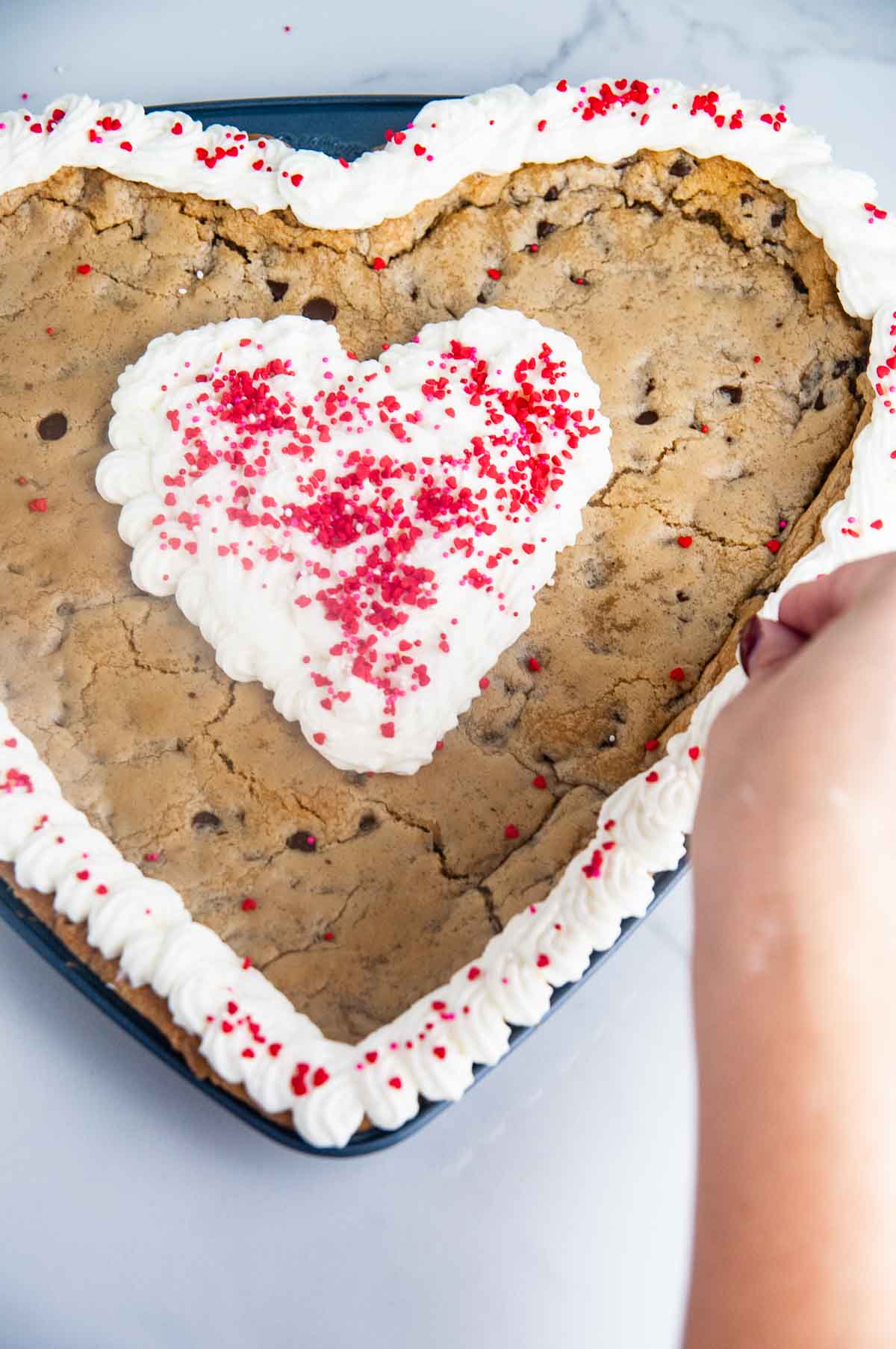 Decorate the giant heart cookie cake with buttercream and sprinkles!