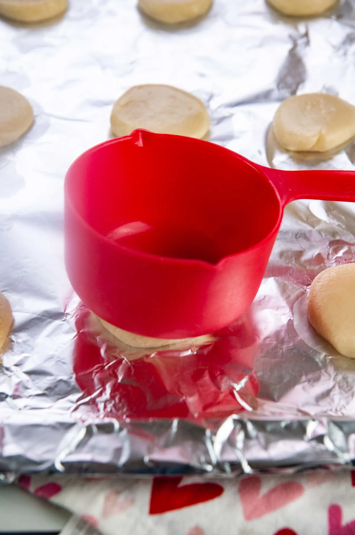 Flatten the sugar cookie dough gently with a measuring cup.
