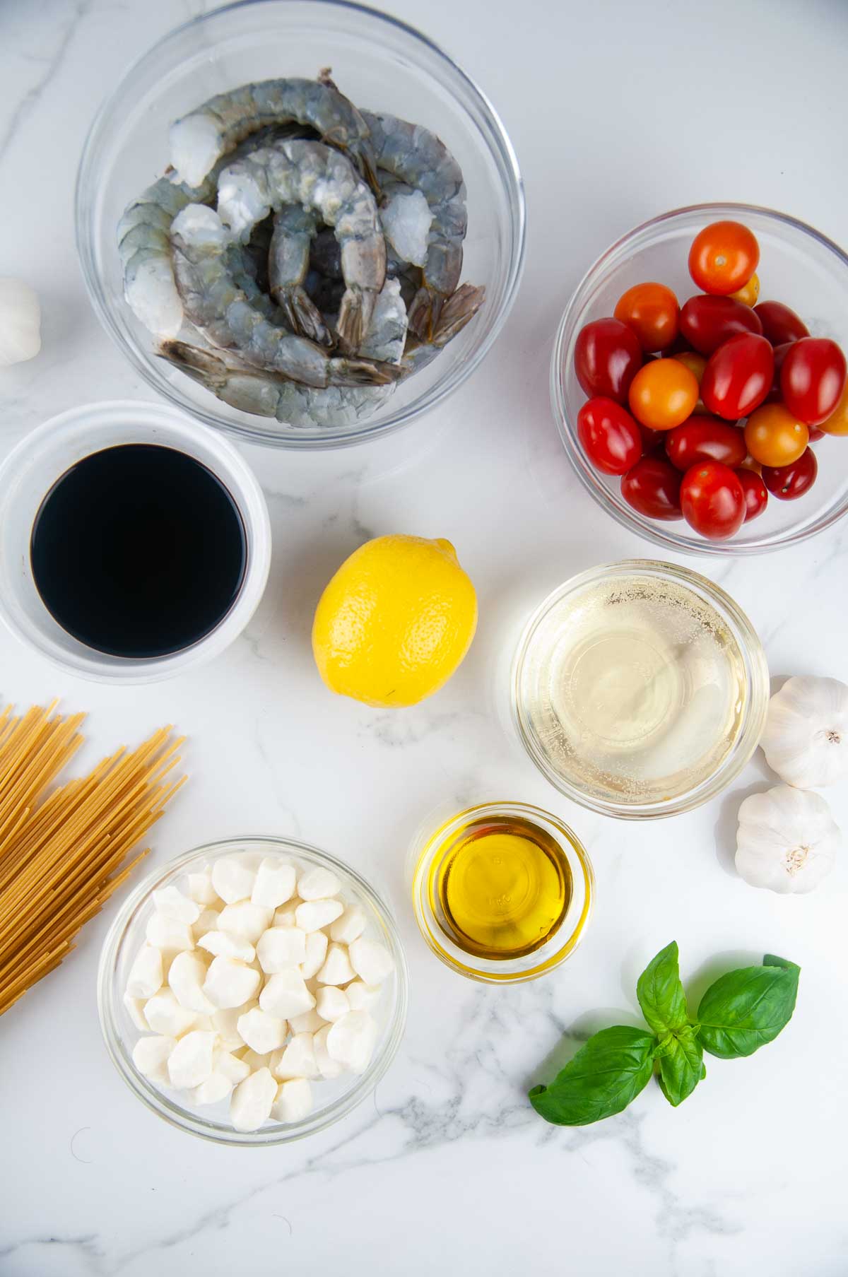 Ingredients for shrimp caprese pasta: shrimp, tomatoes, balsamic vinegar, pasta, mozzarella, lemon juice, olive oil, white wine, garlic, basil