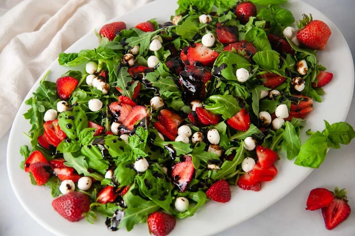 Strawberry Caprese salad is a classic summer meal. This light dish bursts with the sweetness of the fresh berries and basil, spicy arugula and creamy bites of mozzarella. A sweet balsamic drizzles coats adds the finishing touch.